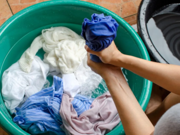 Person washing work uniforms by hand, demonstrating proper uniform care to maintain fabric quality, appearance, and durability.